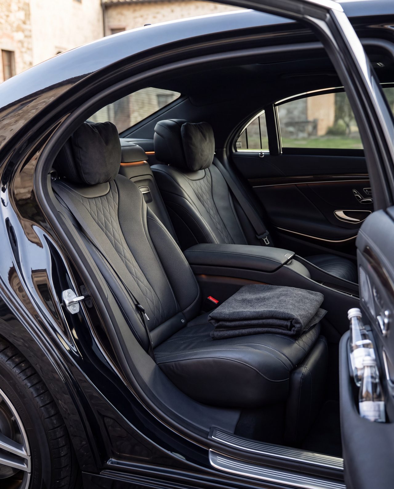 I sedili posteriori in pelle nera di una Mercedes Classe S, con la coperta e l'acqua
