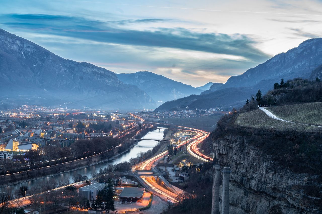 La valle di Trento al crepuscolo, con le luci della città e dell'autostrada